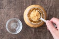 Glass jar of minced garlic and small glass bowl on wood background, womanÃ¢â¬â¢s hand using tablespoon to scoop out garlic Royalty Free Stock Photo