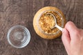 Glass jar of minced garlic and small glass bowl on wood background, womanÃ¢â¬â¢s hand using tablespoon to scoop out garlic