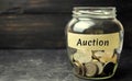 Glass jar with money and the inscription `Auction`. Public sales, property of enterprises, bargaining. Organization of auction tra