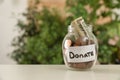 Glass jar with money and label DONATE on table Royalty Free Stock Photo