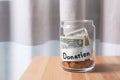 Glass jar with money and label DONATION on table against blurred background. Royalty Free Stock Photo