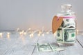 Glass jar with money and paper heart on wooden background