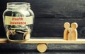 Glass jar with money and the words `Health Insurance` and the family on the scales. The concept of medical insurance of life, fami