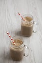 Glass jar mugs filled with coffee, oat and banana smoothie on a white wooden background, low angle view. Copy space Royalty Free Stock Photo