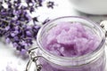 Glass jar of natural sugar scrub and lavender flowers on table, closeup with space for text