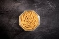 Glass jar with open macaroni pasta on a dark background Royalty Free Stock Photo