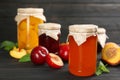 Glass jar of peach jam and fresh fruits on black wooden table Royalty Free Stock Photo