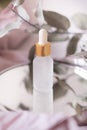 Glass jar with a pipette, serum, oil or essence on a background of eucalyptus foliage. Anti-aging cosmetics