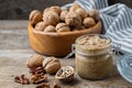 Glass jar of raw organic walnut butter and fresh nuts in bowl on table.