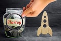 Glass jar, rocket and the word `Startup`. The concept of raising funds for a startup. Charitable contributions to translate ideas Royalty Free Stock Photo