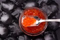 Glass jar with salmon caviar standing in the middle of ice cubes on black slate plate Royalty Free Stock Photo