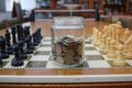 glass jar of savings on the chessboard of higher interest rates Royalty Free Stock Photo