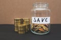 Glass jar with savings coins and stacks of coins. Financial concept.