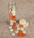 Glass jar with small colored candies on a canvas background Royalty Free Stock Photo
