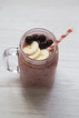 Glass jar with smoothie made of banana, black currant, coconut milk over white wooden background, Royalty Free Stock Photo