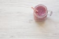 Glass jar with smoothie made of banana, black currant, coconut milk on a white wooden background, top view. Copy space Royalty Free Stock Photo