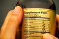 Glass jar with supplement facts in woman hands.