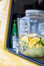 A glass jar with tap full of lemonade with lemon and mint in yellow food truck