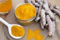 Glass jar of turmeric powder and roots on wooden table Royalty Free Stock Photo