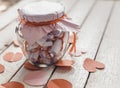 Glass jar on wood. Valentine`s day concept. Date Jar with desires. Red paper hearts at background Royalty Free Stock Photo