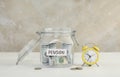 Glass jar with word Pension, dollar banknotes, coins and alarm clock on white table Royalty Free Stock Photo