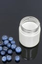 Glass jar with yogurt and blueberries on a black background. Royalty Free Stock Photo