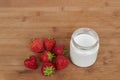 Glass jar with yogurt and seven strawberries on a wooden background. Royalty Free Stock Photo