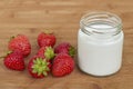 Glass jar with yogurt and seven strawberries on a wooden background. Royalty Free Stock Photo