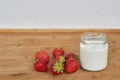 Glass jar with yogurt and seven strawberries on a wooden background horizontal. Royalty Free Stock Photo