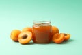 Glass jars with apricot jam and ingredients on background, space for text