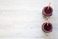 Glass jars with berry smoothie on white wooden table, top view.