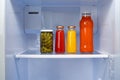 Glass jars of canned products on a fridge shelf
