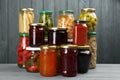 Glass jars with different pickled foods on wooden background