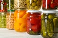 Glass jars with different pickled foods on wooden background, closeup