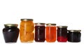 Glass jars with different pickled fruits and jams on background