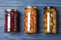 Glass jars with different pickled vegetables on blue wooden table, flat lay Royalty Free Stock Photo