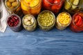 Glass jars with different pickled vegetables on blue wooden table, flat lay. Space for text Royalty Free Stock Photo