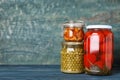 Glass jars with different pickled vegetables on blue wooden table Royalty Free Stock Photo