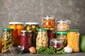 Glass jars with different pickled vegetables on table