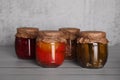 Glass jars with different preserved vegetables on wooden table Royalty Free Stock Photo