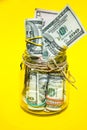 Glass jars filled with Dollar bills, savings inside glass jar, money isolated on yellow background, copy space for text Royalty Free Stock Photo