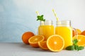 Glass jars with fresh orange juice and tubule, oranges and mint on white table against color background, space for text Royalty Free Stock Photo