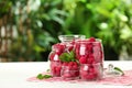 Glass jars with fresh ripe raspberries on table outdoors