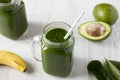 Glass jars full of green smoothie with spinach, avocado and banana, low angle view. Close-up