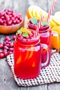 Glass jars of homemade juice with orange slices and wild cranberry