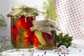 Glass jars with homemade pickled tomatoes, sealed with metal lid on yellow background. pickled cucumbers, dill sprigs