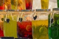 Glass jars with multi-colored lemonade. Bright summer drinks with fruits and herbs