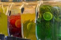 Glass jars with multi-colored lemonade. Bright summer drinks with fruits and herbs