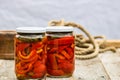 Glass jars with pickled red bell peppers.Preserved food concept, canned vegetables isolated in a rustic composition Royalty Free Stock Photo