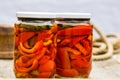 Glass jars with pickled red bell peppers.Preserved food concept, canned vegetables isolated in a rustic composition Royalty Free Stock Photo